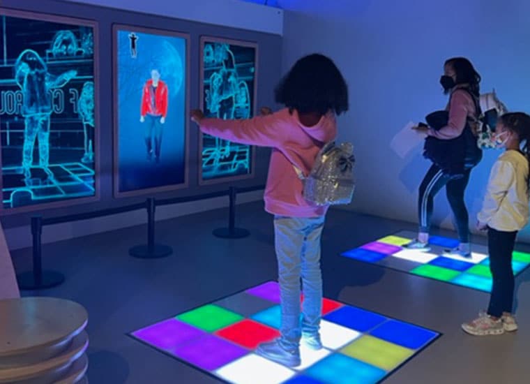 A Student standing on a lit up board of squares at the museum