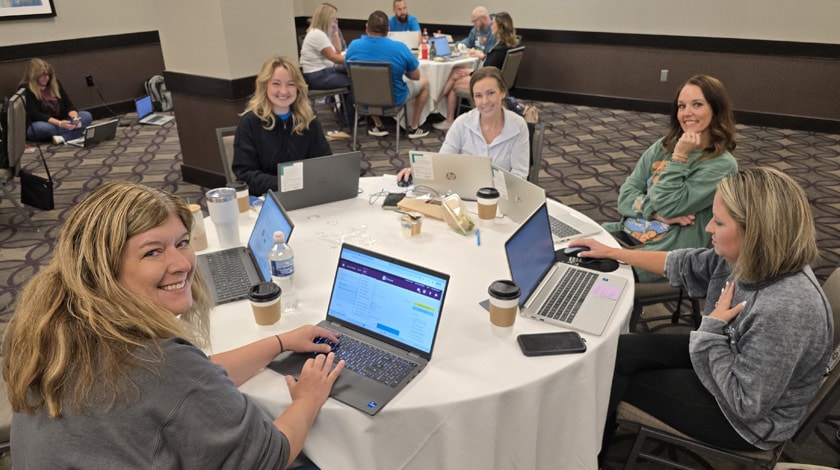 Arkansas Connections Academy staff sitting together at a round table with their laptops open