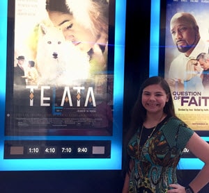 Malarie standing in front of a movie poster that she stars in