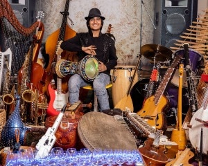 Neil sitting in a chair surrounded by musical instruments.