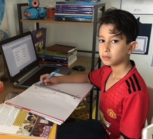Talal sitting at his workspace for online school