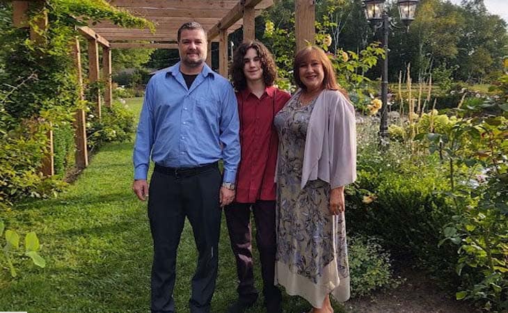 Image of Derek C. with his family in a flower field.