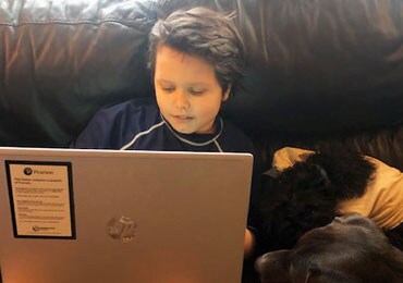 Henry sitting on his couch on his laptop