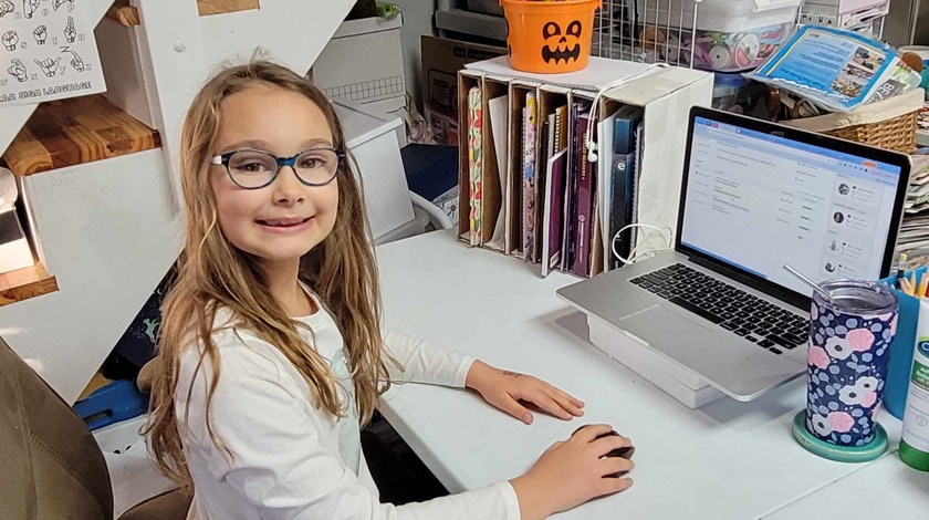 Juliet in her learning space, sitting at a desk with her laptop open in front of her. 