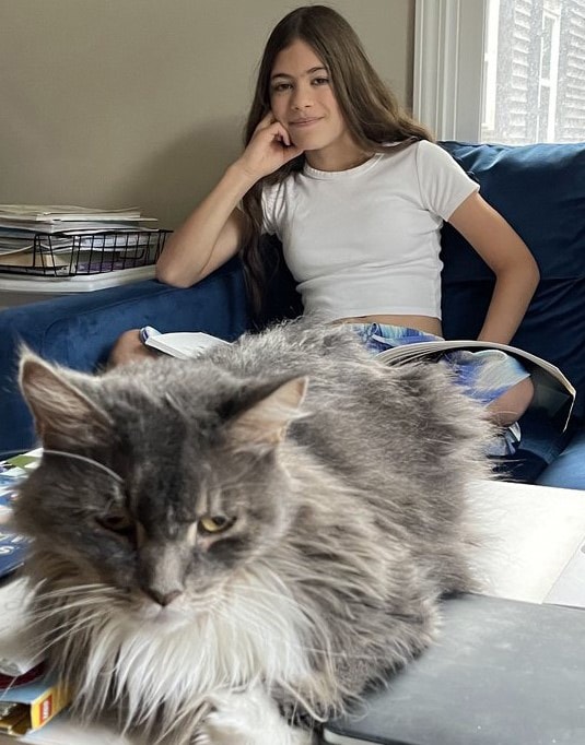 Natasa sitting on a couch with her cat close by. 