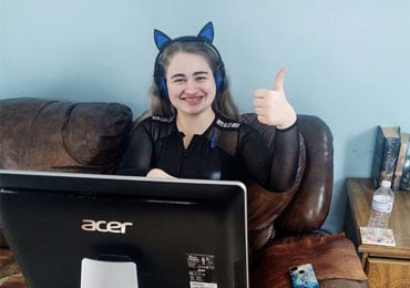 Kayla holding her thumbs up and attending online school