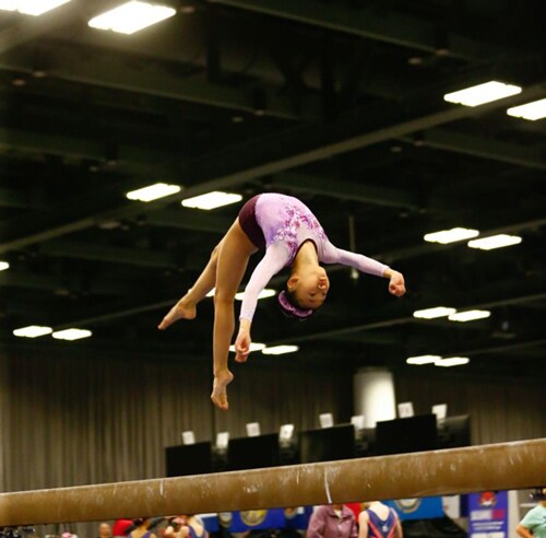 Marian doing an impressive flip on a balance beam