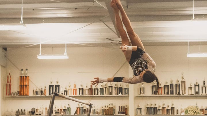 Action shot of Mallory mid-jump from a gymnastics bar