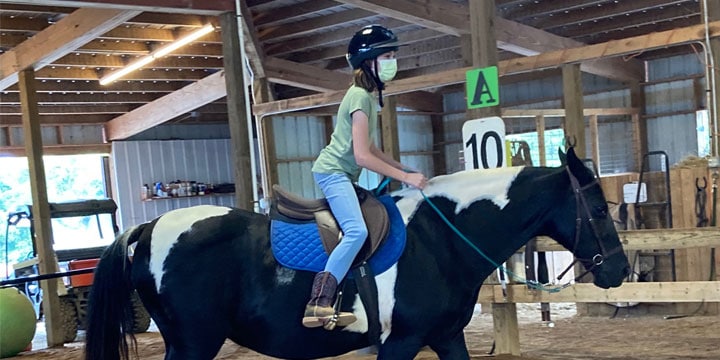 Alison riding her paint horse at competition