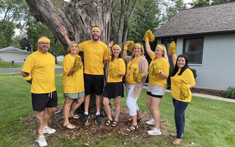 A group of Wisconsin Connections Academy staff posing together in front of a tree