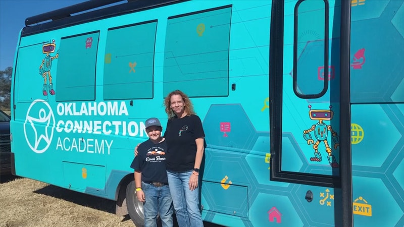 An adult and student standing in front of the Exploration Station bus