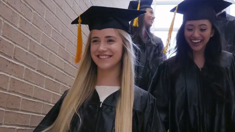 Happy students wearing graduation gowns