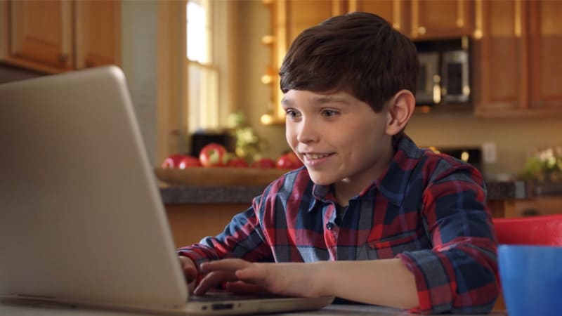 An online elementary school student working on his laptop