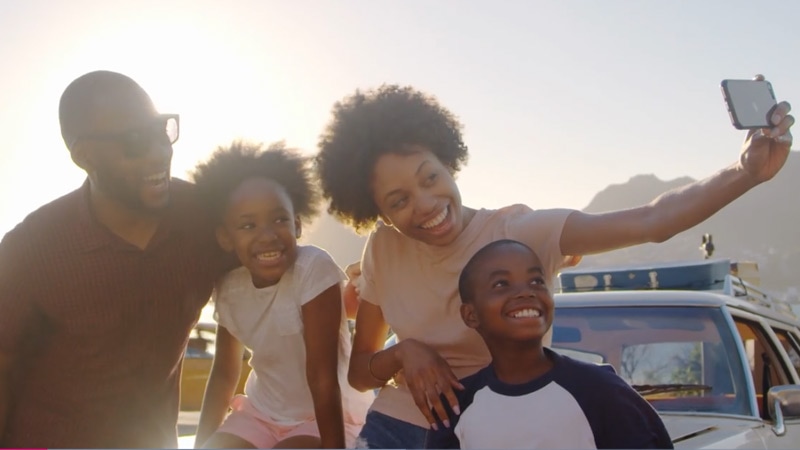 A family of four taking a selfie together on a road trip