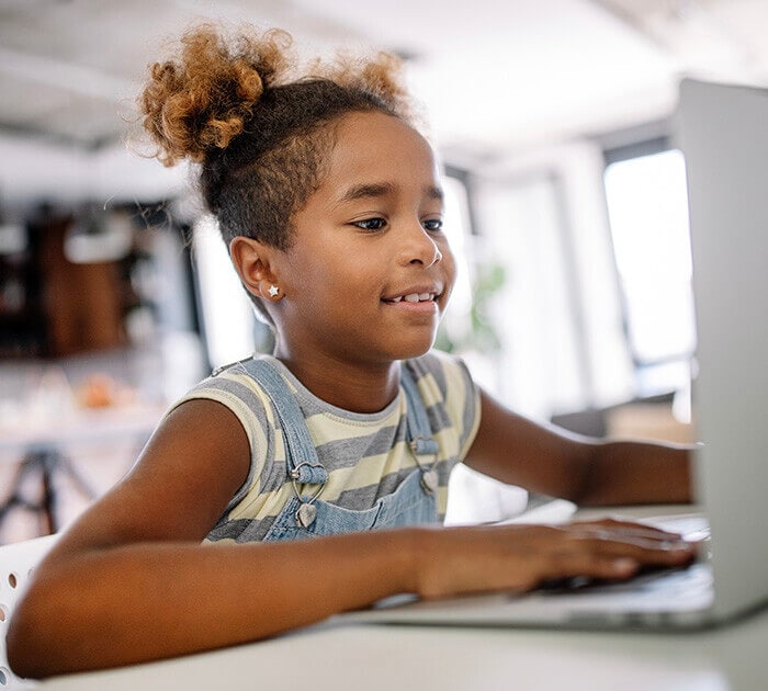 A young girl is sitting at her computer