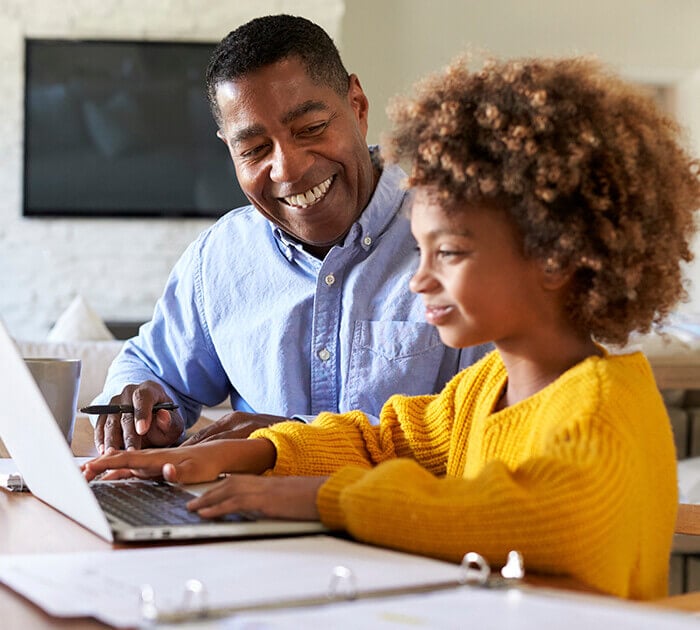 A father helping his daughter with school work on a laptop