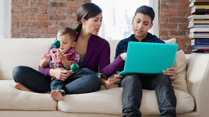 A mother is helping her son with his homework on a laptop
