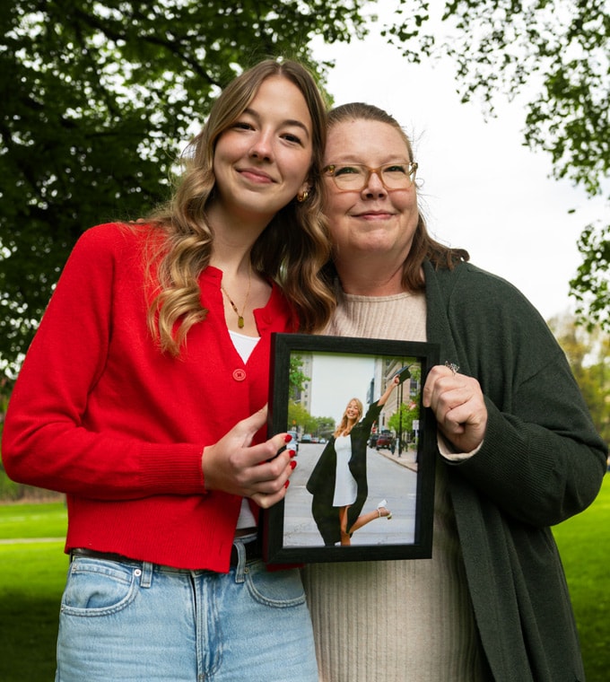 Connections Academy graduate, Megan, and her mom holding up a photo of her Megan wearing a graduation gown and holding a cap