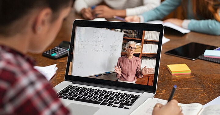 A student is watching an online lesson on a laptop