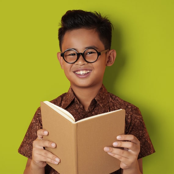 A young boy smiling and holding a book