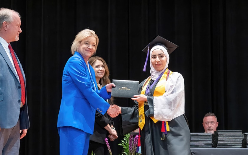 An Alabama Connections Academy student accepting diploma and shaking hands with the school leader