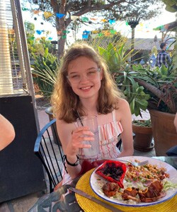 Image of Lilyana P, a young student at Arizona Connections Academy. She is pictured here eating a meal and sipping on some water. 