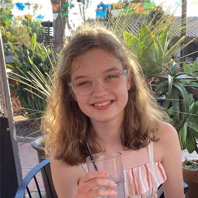 Image of Liliana P, a student at Arizona Connections Academy. She is wearing a pink dress and is sipping water.