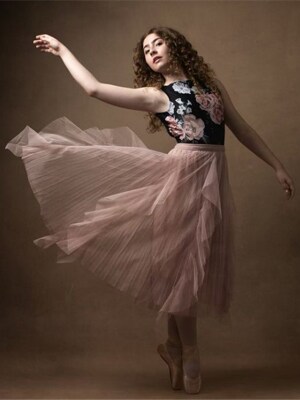 Image of Ashlyn Hall, a freshman at Arizona Connections Academy. She is wearing a pink tulle skirt and a black flowery top and is on pointe.  