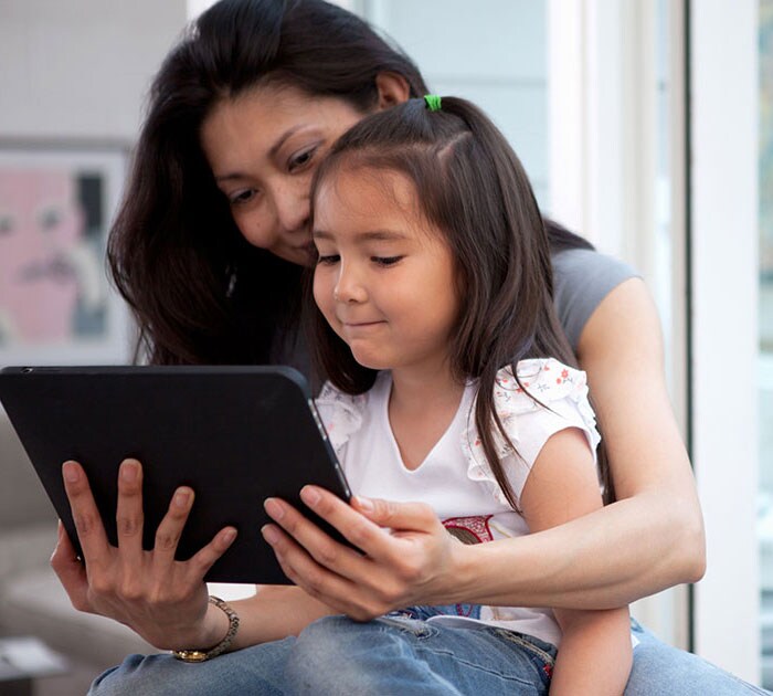 A learning coach and connections academy elementary school student look at a tablet together