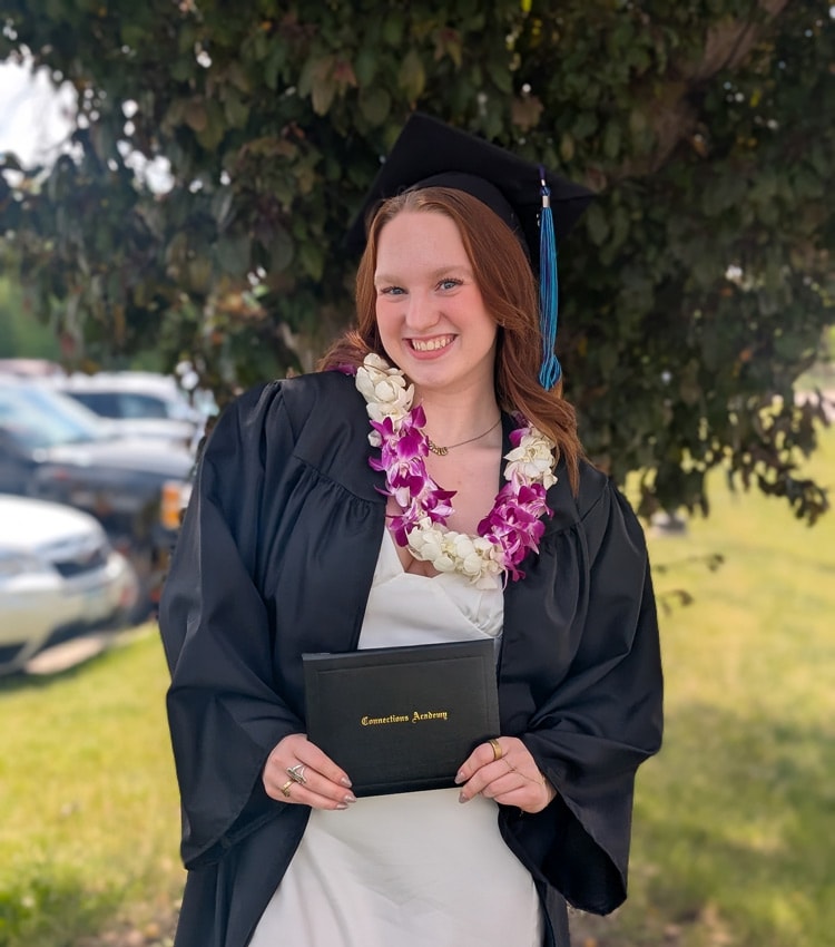 Maile wearing a cap and grown and holding her Connections Acadedy diploma