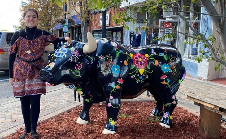 Aiyana, a student at Minnesota Connections Academy standing next to a decorated bull statue.