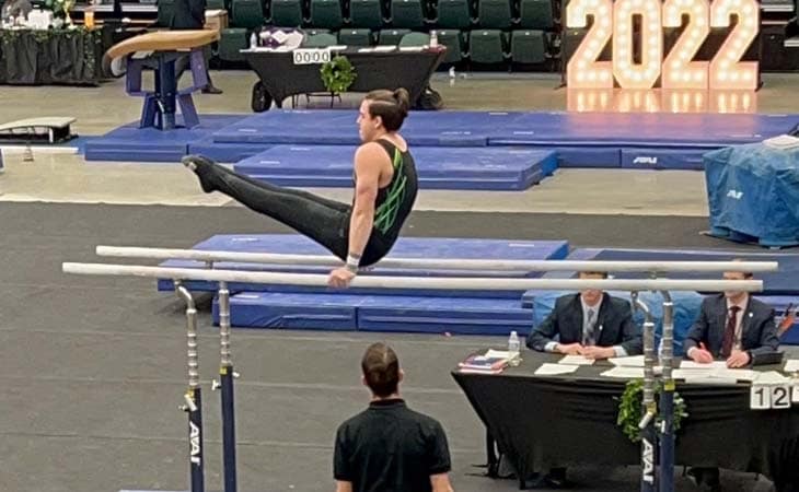 A student from Minnesota Connections Academy performing a pike on the parallel bars.