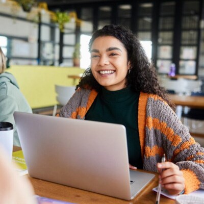 A student in an orange and grey swewater smiling at the camera while taking a math online class at Connections Academy. 