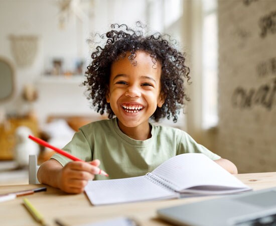 Connections Academy smiling student in a green shirt and a red pen. 
