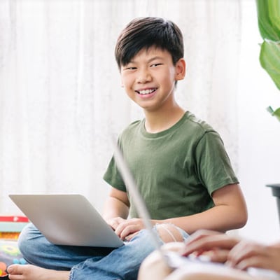 A student in an green shirt smiling at the camera while taking a math online class at Connections Academy. 