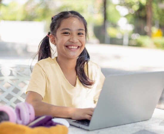 Connections Academy smiling student in a purple shirt working on an Math assignment. 