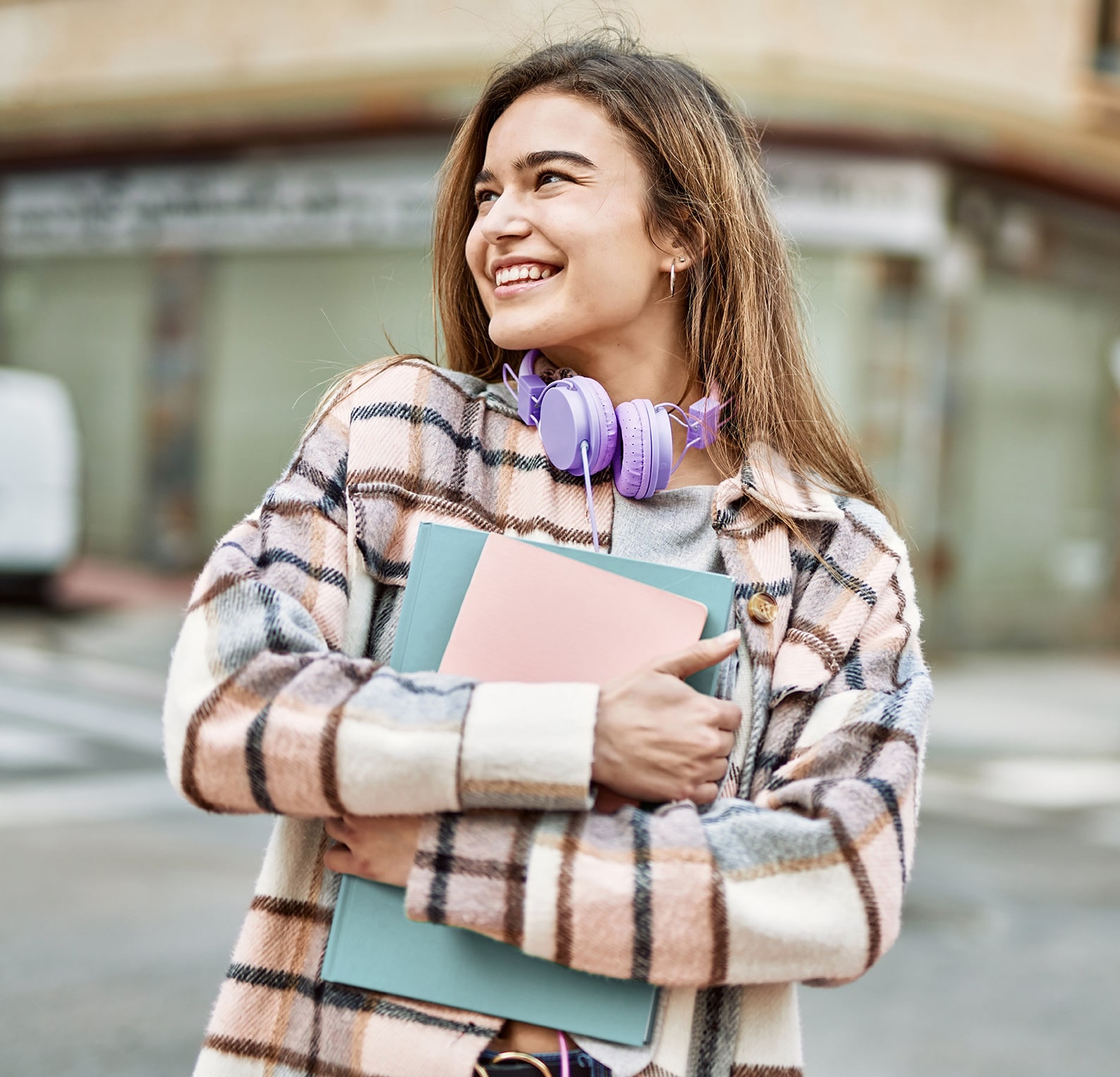 Student holding her schoolwork and headphones.