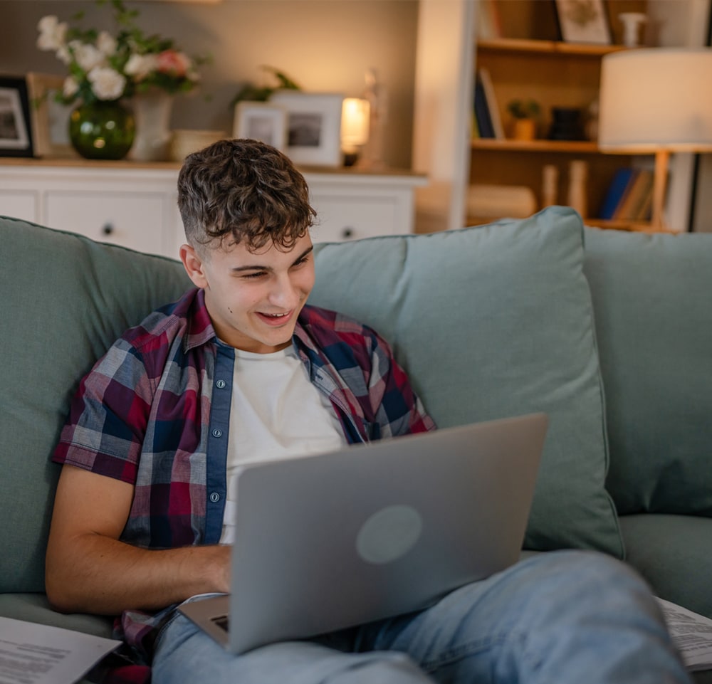 Student sitting on a couch with a laptop in his lap