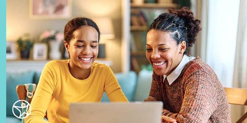 young girl and adult woman look at laptop