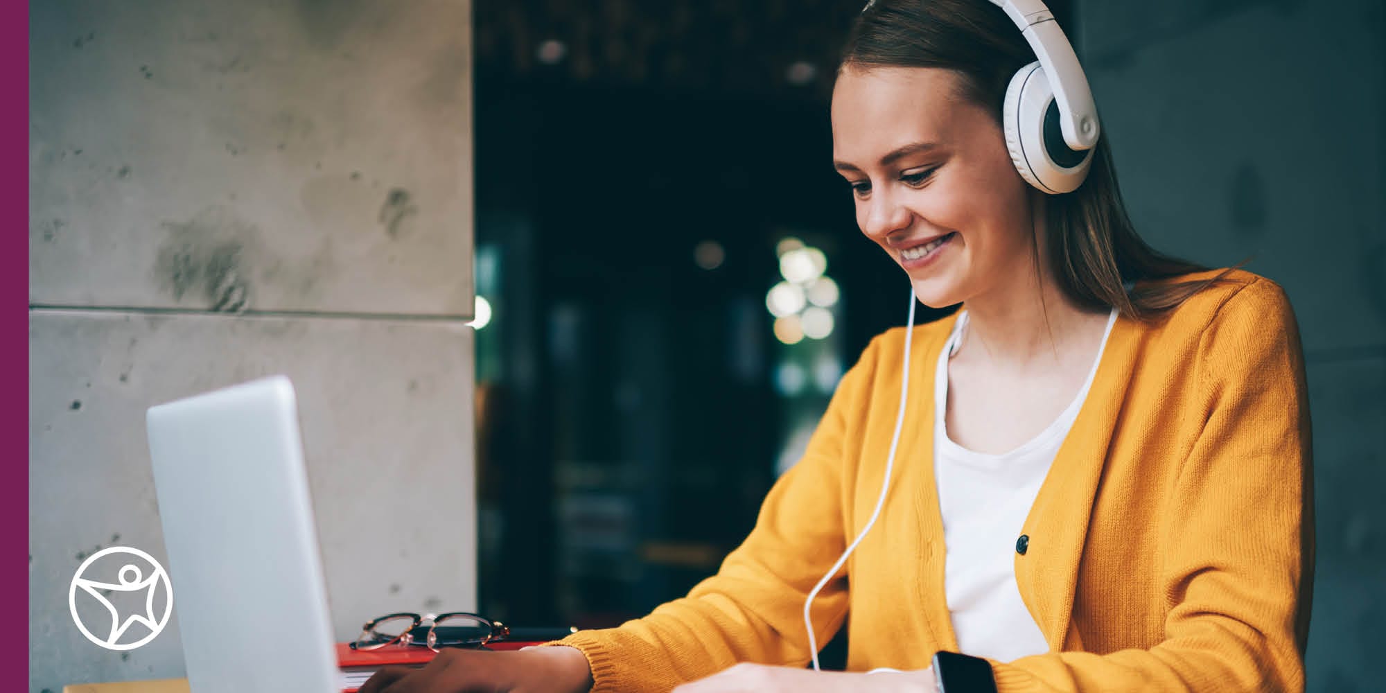 A teenage girl wearing headphones and using a laptop