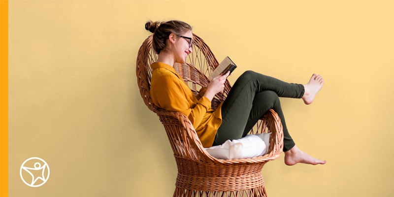 A student sitting on a chair and reading a book.