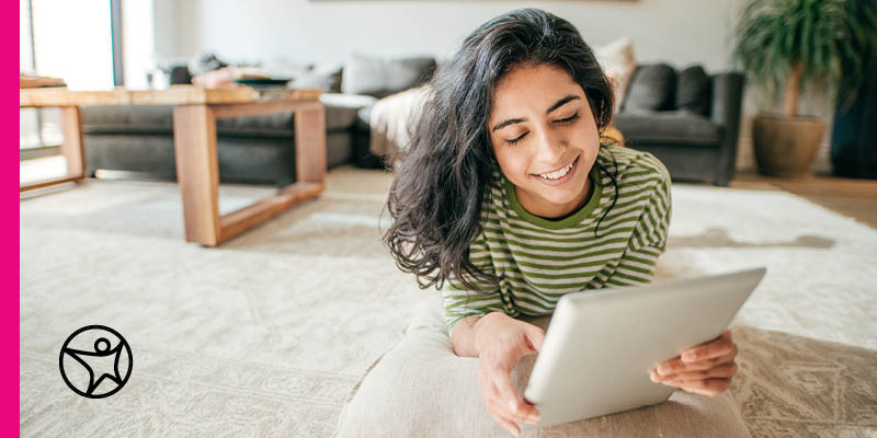 A student laying on the floor and reading on a tablet