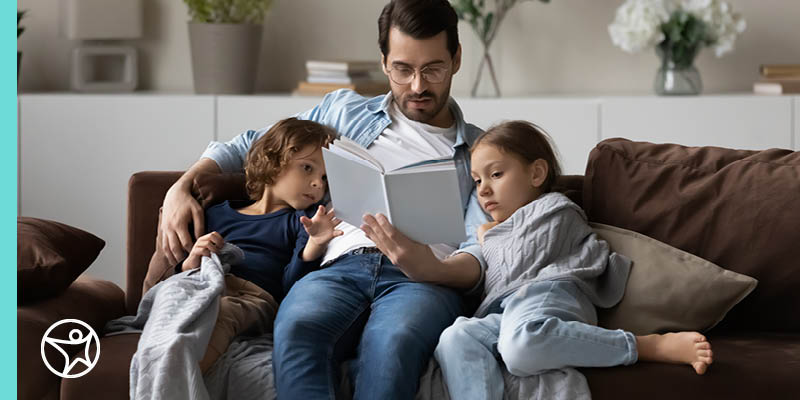 A father is reading a good book to his two daughters