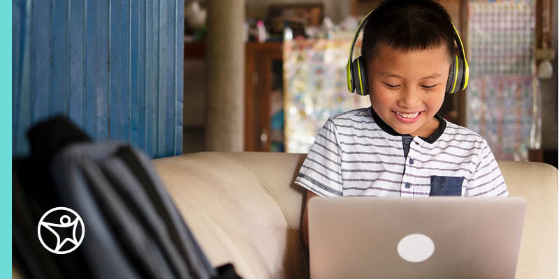 Young student in a yellow shirt and blue headphones taking a Live Lesson class.