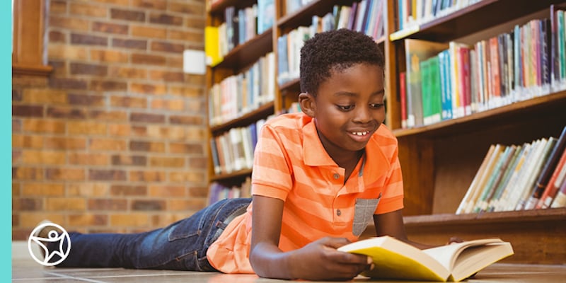 A young boy reading a book on the floor