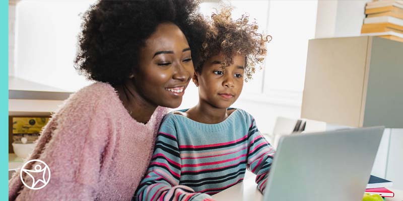 A mother is looking at a laptop with her daughter