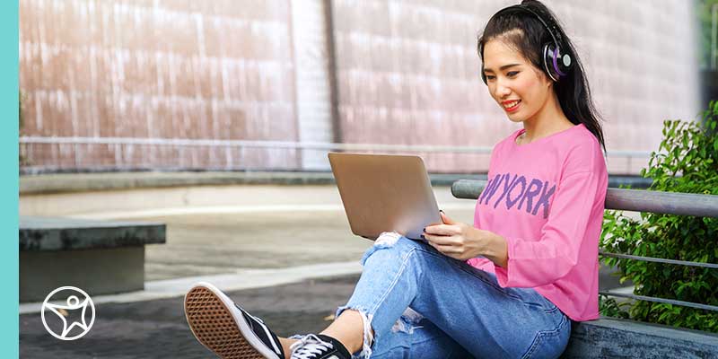 Online private school high school student on laptop outside.