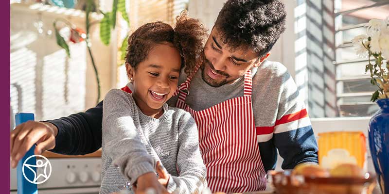 An elementary school age girl baking cookies with her father