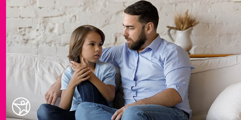 Parent helping child while sitting on a white sofa