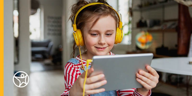 Young female student in a red striped shirt with yellow headphones looking at her tablet while taking an online class at Connections Academy.